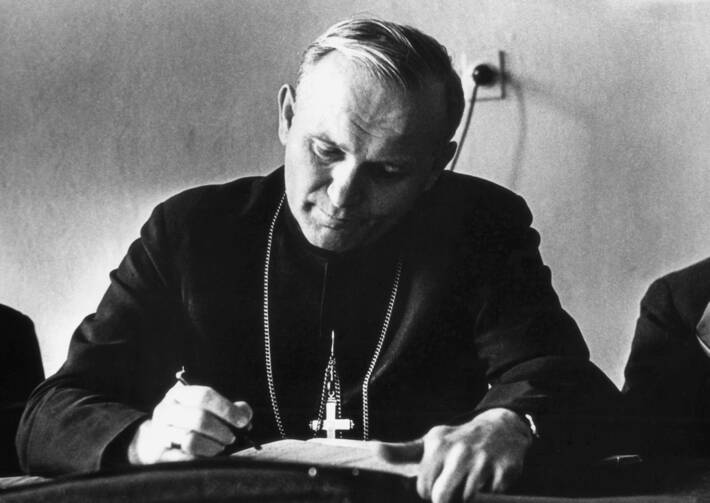 john paul ii writes on a piece of paper in a black and white photo
