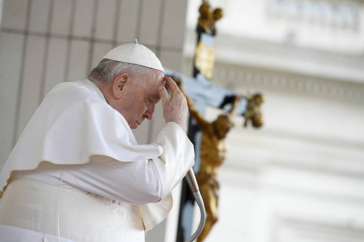 pope francis makes the sign of the cross with a crucifix behind him