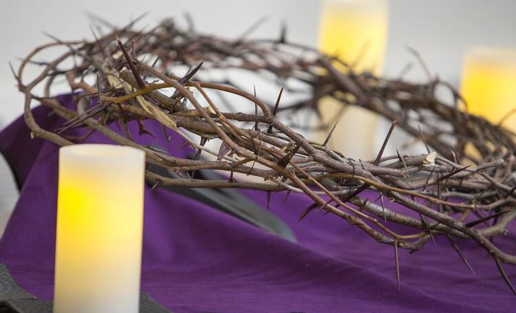 crown of thorns on a purple background with a candle in front