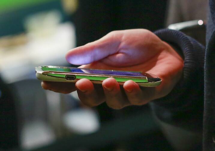 A hand holds a smartphone with an app open on the screen