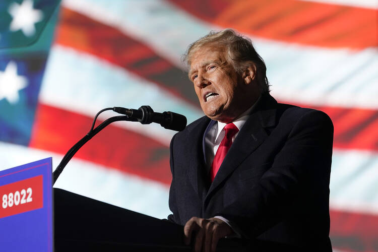 president donald trump speaks at a podium in front of televised american flag