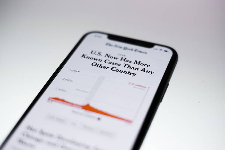 a hand holds a smartphone displaying a new york times article about covid-19