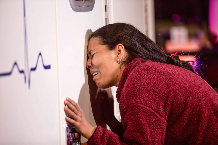 A young woman weeps against an ambulance as a loved one is treated by medics after a fire broke out at the Mexican Immigration Detention center in Ciudad Juárez on Monday, March, 27, 2023. (Omar Ornelas/The El Paso Times via AP)