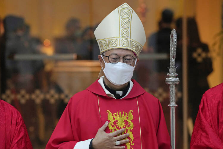 Catholic Bishop Stephen Chow of Hong Kong in a red chasuble and white mitre wears a surgical mask.