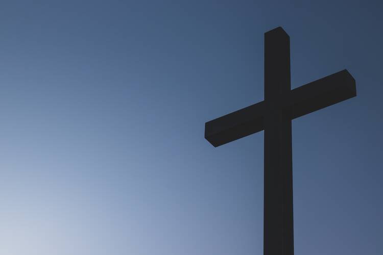 Black cross statue on blue background