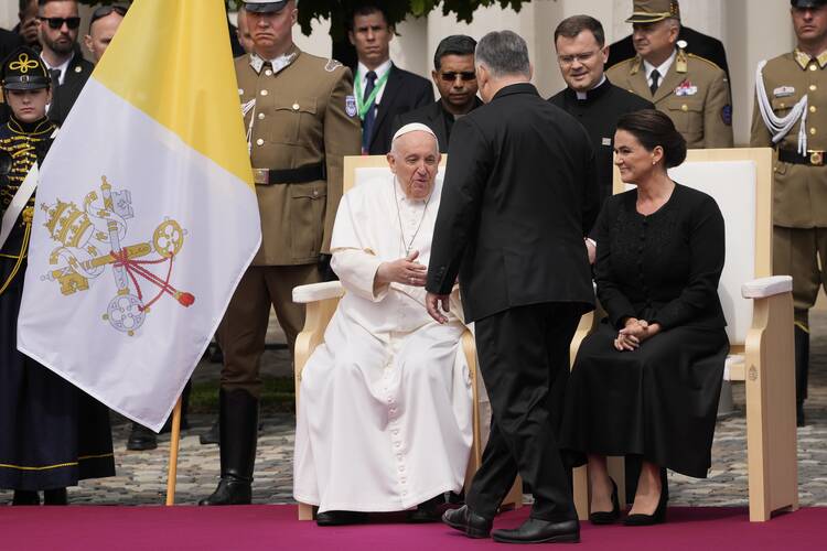 pope francis in white, seated next to hungary's president dressed in black, greets hungary's prime minister 