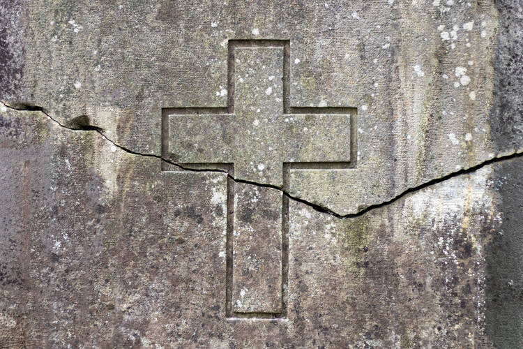 engraving on a cross on a stone wall with a crack across the middle