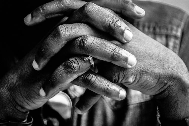 a black woman's hands folded in prayer in a black and white photo