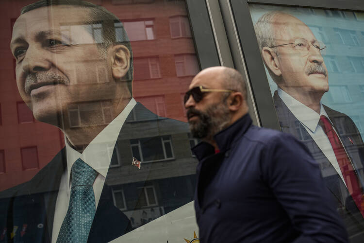 A pedestrian passes before campaign billboards of Turkish President and People's Alliance's presidential candidate Recep Tayyip Erdogan, left, and CHP party leader and Nation Alliance's presidential candidate Kemal Kilicdaroglu in Istanbul on May 5. (AP Photo/Emrah Gurel)