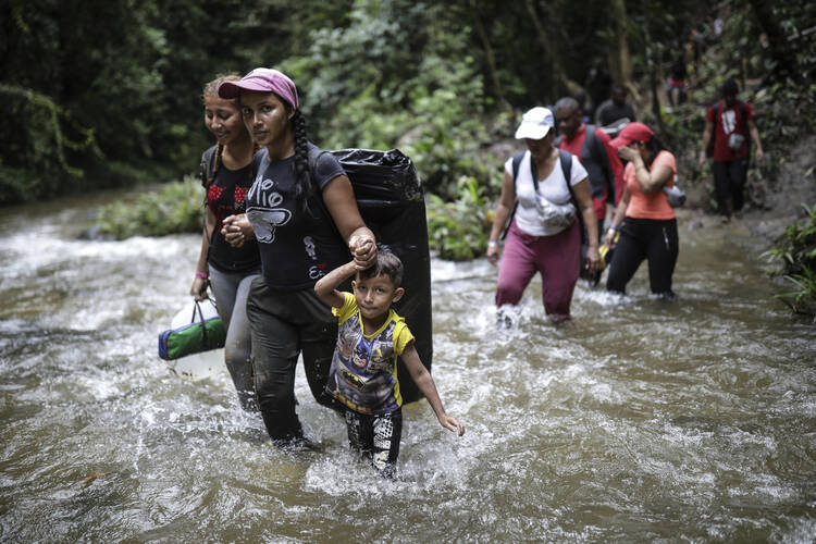Migrants wade across a river during as they trek across the Darien Gap from Colombia to Panama, in hopes of reaching the U.S., Wednesday, May 10, 2023. Pandemic-related U.S. asylum restrictions, known as Title 42, are to expire Thursday, May 11. (AP Photo/Ivan Valencia)