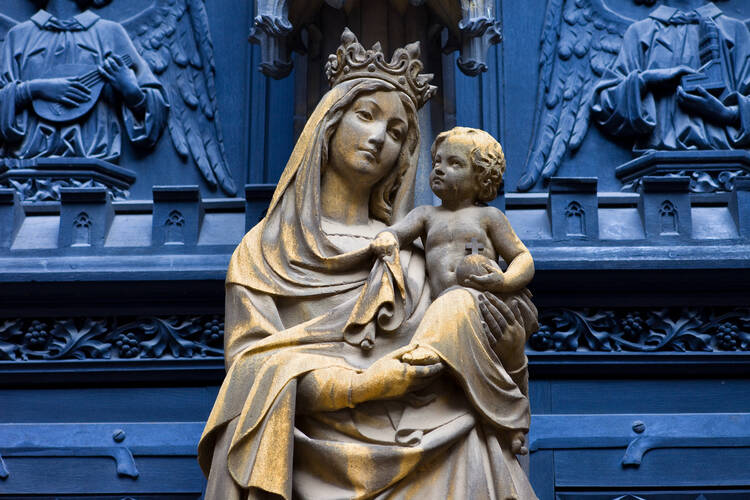 a statue of mary with baby jesus in front of a blue background