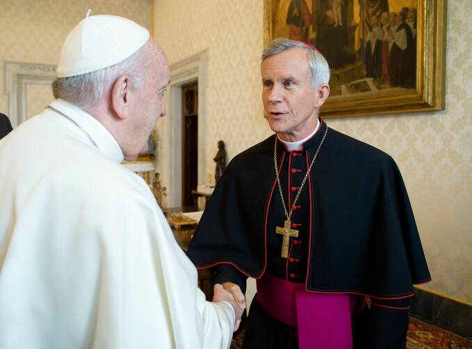 bishop strickland wears his clerics while greeting pope francis whose back is turned to the camera. bishop strickland is a 64 year old average sized white man with graying hair