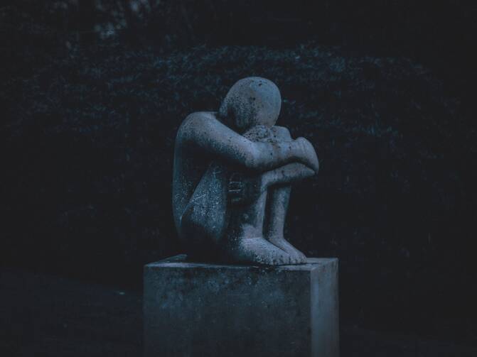 Man hugging his knees statue