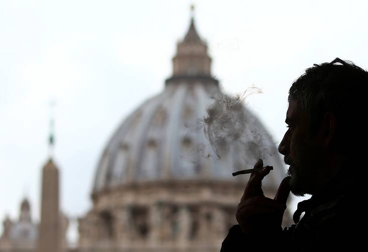 a silhouette of a man smoking in front of the vatican