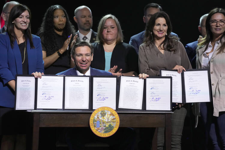 Florida Gov. Ron DeSantis holds up bills he signed during a bill signing ceremony at the Coastal Community Church at Lighthouse Point on May 16, 2023, in Lighthouse Point, Fla. (AP Photo/Wilfredo Lee)