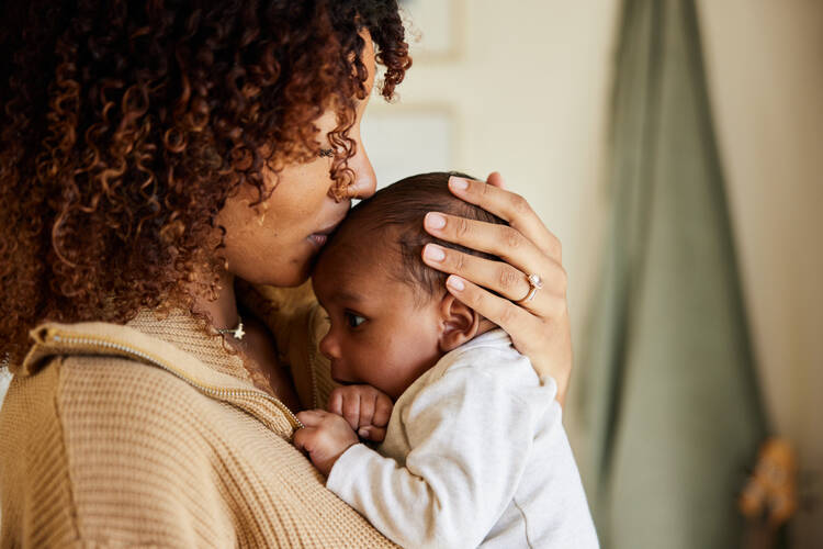 A Black mother holds her infant child. (iStock/Goodboy Picture Company)