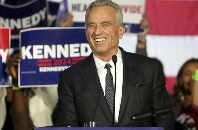 Robert F. Kennedy Jr. stands in front of kennedy 2024 signs at a rally