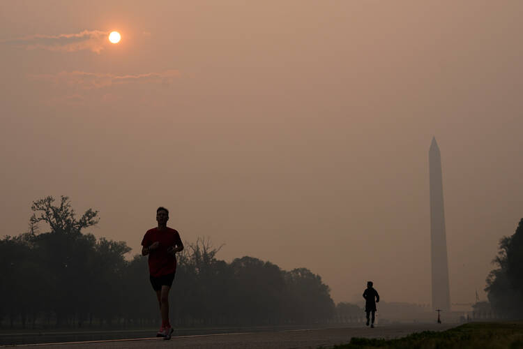 Joggers trot along the Reflecting Pool with the sun rising over the Washington Memorial and a thick layer of smoke, Thursday, June 8, 2023, in Washington. Intense Canadian wildfires are blanketing the northeastern U.S. in a dystopian haze, turning the air acrid, the sky yellowish gray and prompting warnings for vulnerable populations to stay inside. (AP Photo/Julio Cortez)