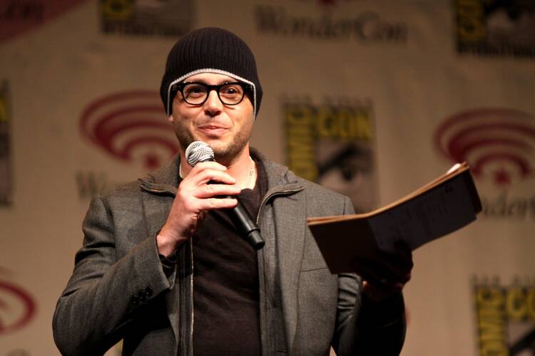 The TV showrunner Damon Lindelof, in glasses and a black knit hat, picture speaking at Comic Con in 2012. 