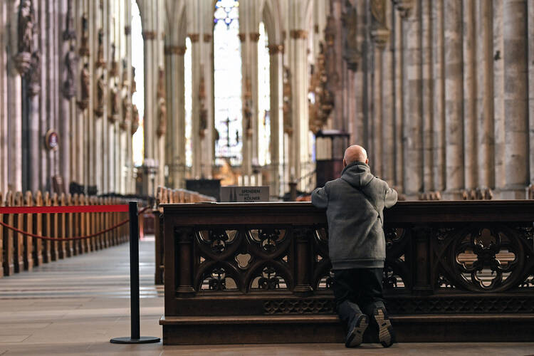 A man kneels in a Catholic church in Germany