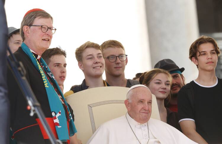 Cardinal Woelki stands next to seated Pope Francis. 