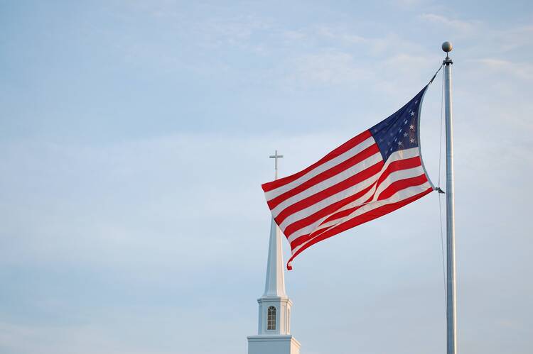 american flag waves in front of a church steeple