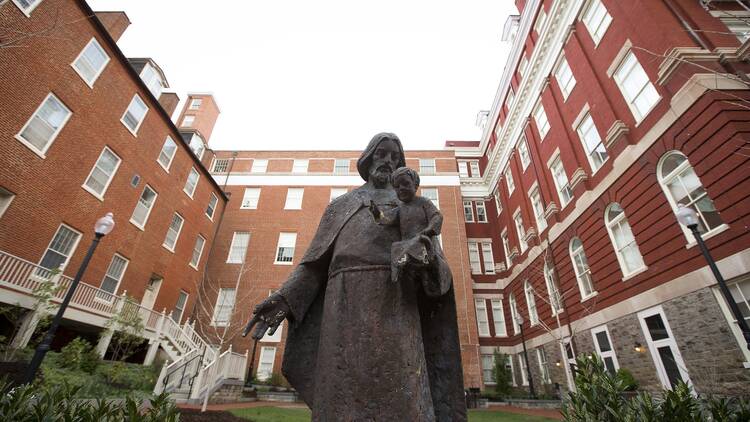 Statue of an enslaved person in front of Georgetown buildings. 