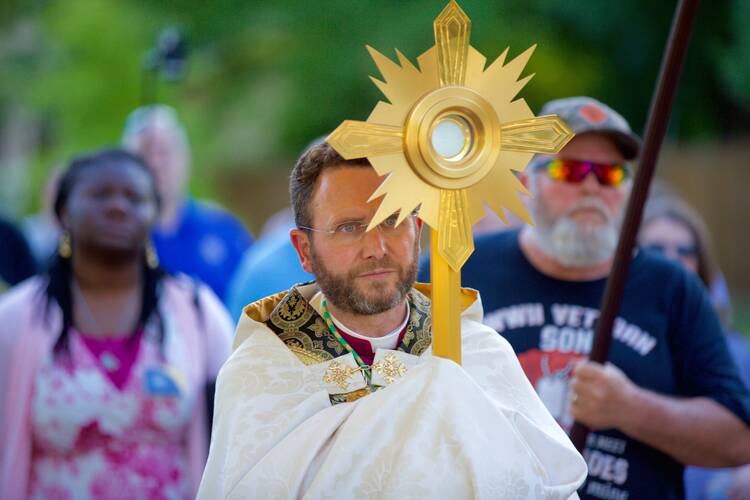 Auxiliary Bishop Andrew H. Cozzens of St. Paul and Minneapolis carries the Eucharist in a monstrance during a procession June 19, 2021. 