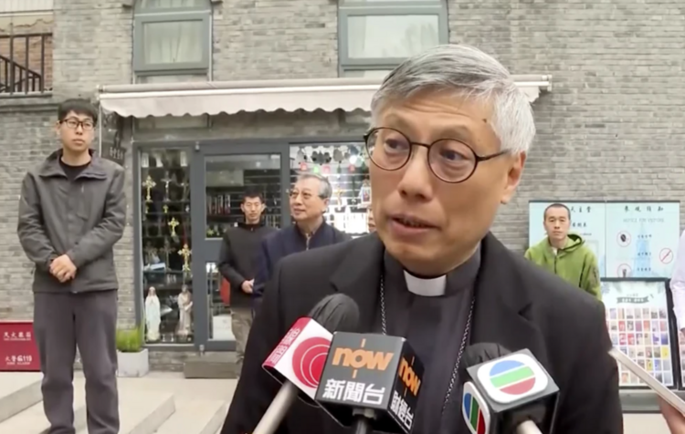 Bishop Stephen Chow speaks into several microphones.