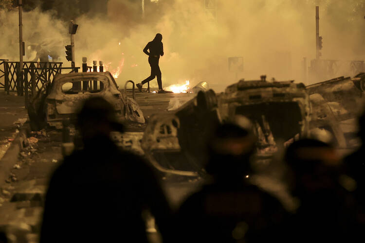 A demonstrator runs on the third night of protests sparked by the fatal police shooting of a 17-year-old driver in the Paris suburb of Nanterre, France, Friday, June 30, 2023. Widespread riots in France sparked by the police killing of a teenager with North African roots have revealed the depth of discontent roiling poor neighborhoods — and given a new platform to the increasingly emboldened far right. (AP Photo/Aurelien Morissard, File)