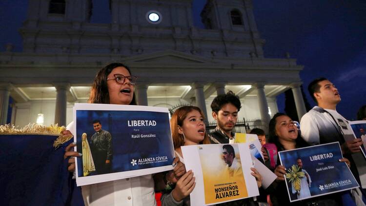 Nicaraguans with signs stand in front of the Metropolitan Cathedral in San Jose, Costa Rica.