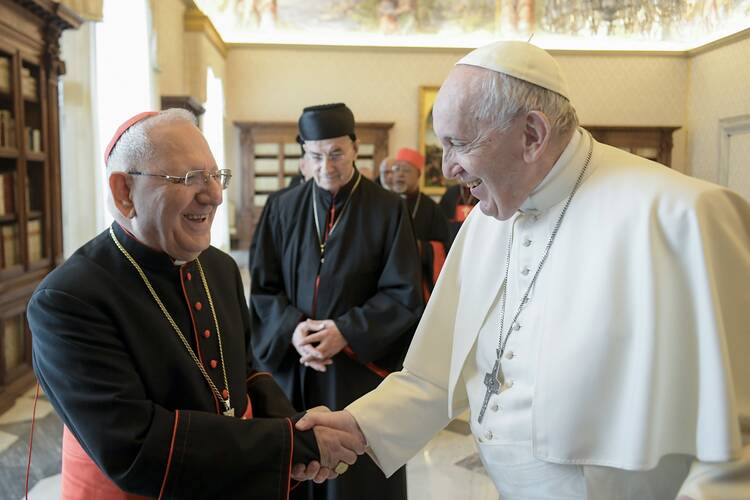 Pope Francis greets Iraqi Cardinal Louis Sako, patriarch of the Chaldean Catholic Church, in the library of the Apostolic Palace at the Vatican on Feb. 18, 2022. (CNS photo/Vatican Media)