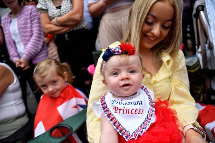 A woman and her baby watch the Orange Order celebrations in Belfast, Northern Ireland, on July 12, 2022. Data from the 2021 census showed 45.7% of respondents identified as Catholic or were brought up Catholic, compared with 43.5% identifying as Protestants, the first time in more than a century that Catholics outnumber Protestants. (CNS photo/Clodagh Kilcoyne, Reuters)