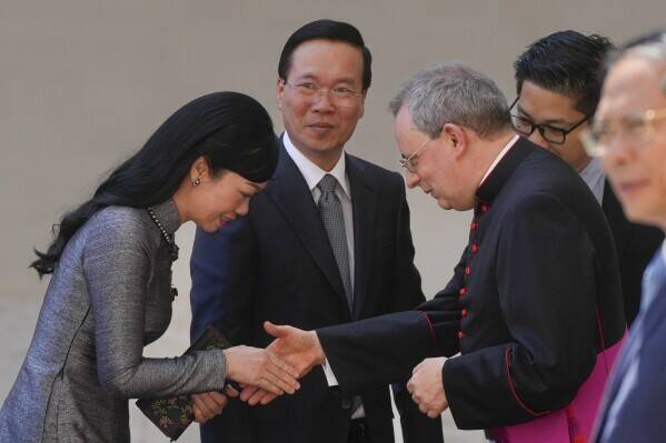 The president of Vietnam and his wife shake hands with a Vatican representative. 