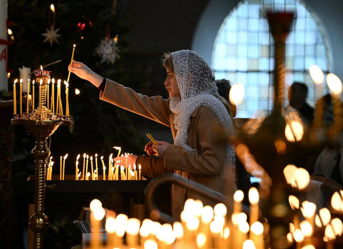 A woman lights a candle in a church. 