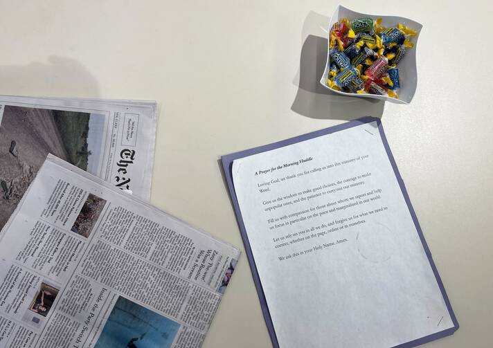 A morning prayer sheet is positioned next to a bowl of Jolley Ranchers and newspapers.