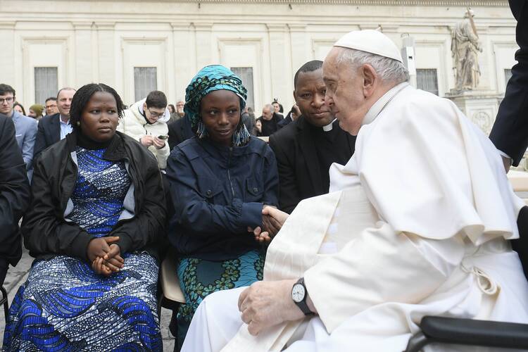 Pope Francis greets Janada Marcus, a survivor of Christian persecution in Nigeria, after his general audience on March 8, 2023. She is accompanied by Father Joseph Bature Fidelis, director of a trauma center for victims of terrorism in Nigeria, and by Maria Joseph, another survivor. (CNS photo/Vatican Media)