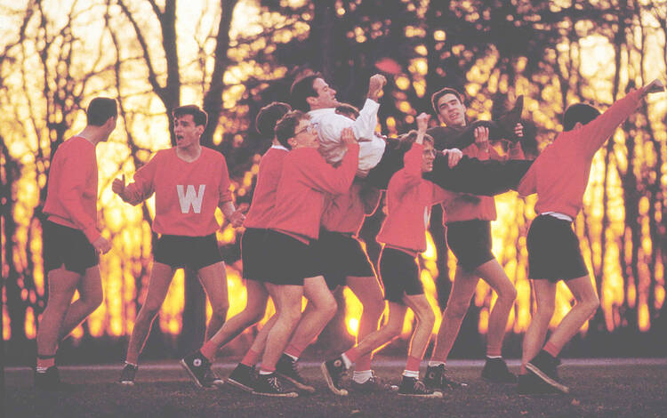 A scene from the film Dead Poets Society of students outside in gym gear carrying their professor, played by Robin Williams