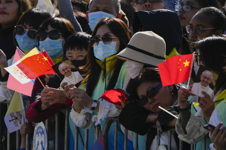 People hold pictures of Pope Francis with the national flags of the People's Republic of China and of the Vatican as they wait for Mongolian President Ukhnaagin Khurelsukh, and Pope Francis to meet, Saturday, Sept. 2, 2023, in front of a gigantic statue of former Khagan of the Mongol Empire Genghis Khan in Sukhbaatar Square in Ulaanbaatar. (AP Photo/Ng Han Guan)