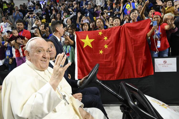 Pope Francis waves as people behind him raise a Chinese flag before the pope's Mass in Steppe Arena in Ulaanbaatar, Mongolia, Sept. 3, 2023. At the end of the Mass, the pope sent greetings to China and to Chinese Catholics. (CNS photo/Vatican Media)