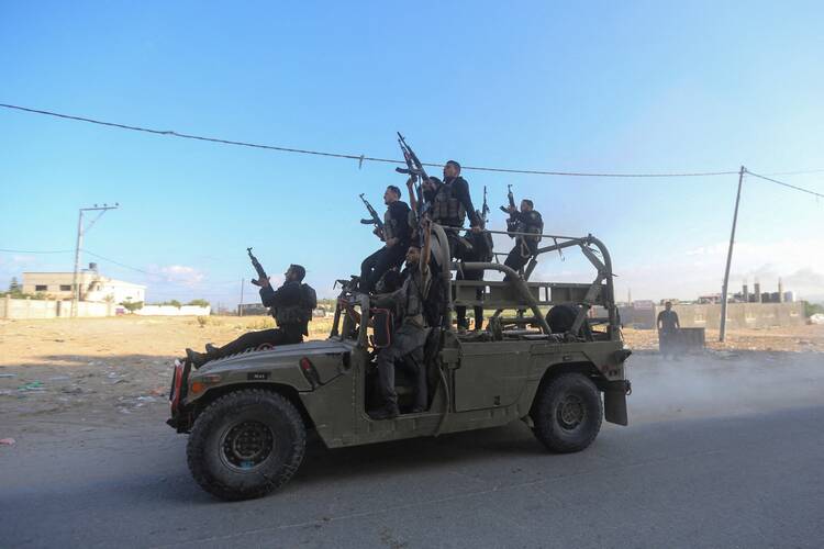 Palestinian militants ride an Israeli military vehicle that was seized by gunmen who infiltrated areas of southern Israel, in the northern Gaza Strip Oct. 7, 2023. At least 70 Israelis, including civilians, were killed and more than 500 injured in an unprecedented surprise dawn attack by Hamas militants who breached Israeli security along the Gaza border. (OSV Newsphoto/Ahmed Zakot, Reuters)