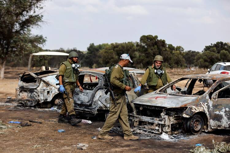 Israeli soldiers inspect the burned cars of festival-goers near Israel's border with the Gaza Strip, in southern Israel, Oct. 13, 2023, at the site of an attack on the Nova Festival by Hamas gunmen from Gaza. (OSV News photo/Amir Cohen, Reuters)