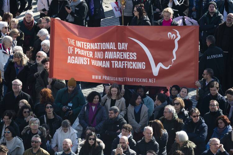 Visitors hold a banner marking the International Day of Prayer and Awareness Against Human Trafficking, as Pope Francis leads the Angelus from the window of his studio overlooking St. Peter’s Square at the Vatican on Feb. 12, 2023. (CNS photo/Vatican Media)