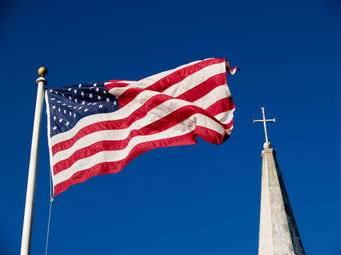 United States flag fluttering with a church steeple in the background (iStock/imdm)