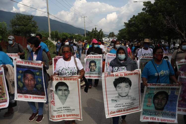 Relatives of missing students hold posters with their images as they take part in a Sept. 27, 2020, march to mark the sixth anniversary of the disappearance of 43 students of the Ayotzinapa Teacher Training College in Iguala, Mexico. The students disappeared in Iguala after they clashed with police and masked men. (CNS photo/Henry Romero, Reuters)