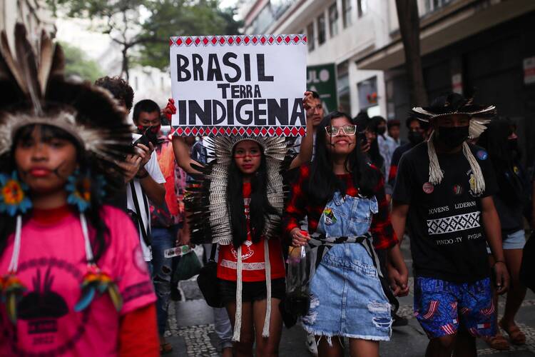 Indigenous people march with a banner that reads "Indigenous Land of Brazil" as they commemorate the International Day of the World's Indigenous People in São Paulo on August 9, 2022.