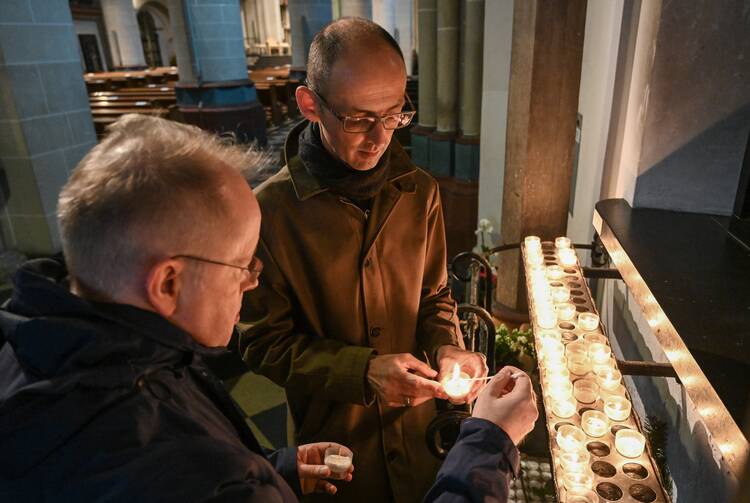 A gay couple lights votive candles at a Catholic church in Essen, Germany, on Oct. 30, 2021. (OSV News photo/Harald Oppitz, KNA)