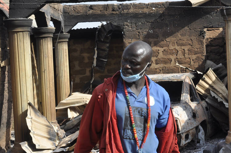 A man stands in front of a burnt out house following an attacked by gunmen in, Bokkos, north central Nigeria, on Dec. 26, 2023. (AP Photo)