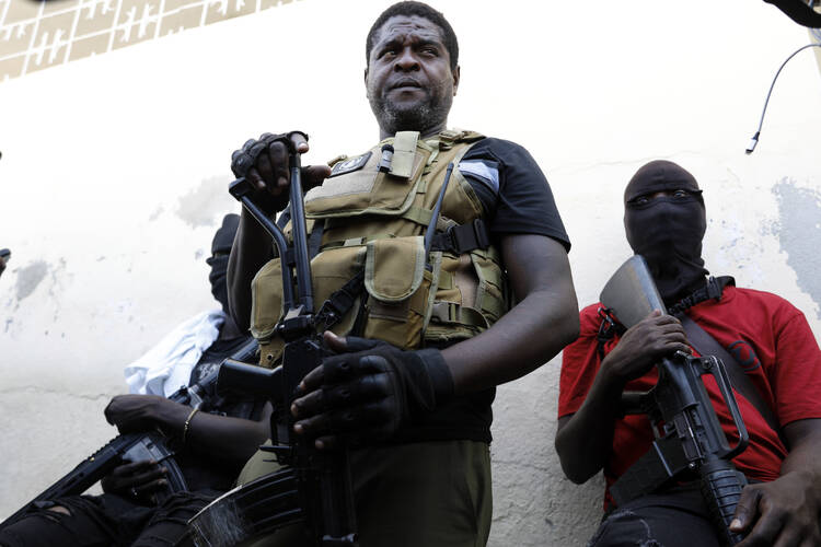 The former police officer Jimmy Chérizier, known as Barbecue, leader of the "G9 and Family" gang, stands with fellow gang members after speaking to journalists in the Delmas 6 neighborhood of Port-au-Prince in Port-au-Prince on March 5. Haiti's latest violence began with a direct challenge from Barbecue, who said he would target government ministers to prevent the prime minister's return and force his resignation. (AP Photo/Odelyn Joseph)