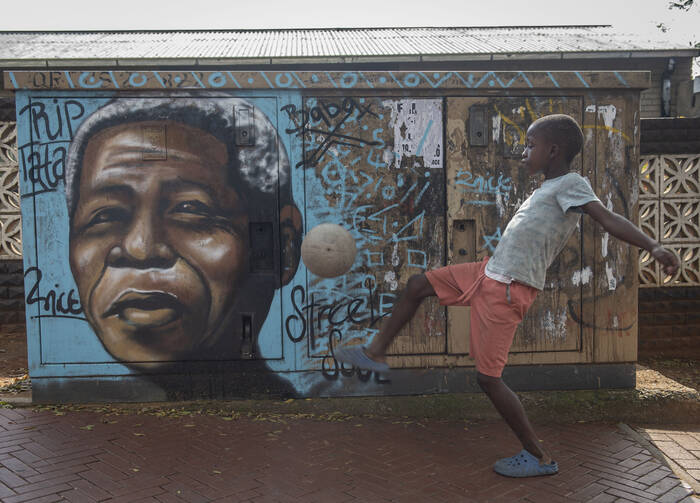 A child kicks a football in front of a mural of Nelson Mandela, in Soweto, South Africa, as the country celebrates Freedom Day on April 27. (AP Photo)